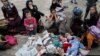 Five Syrian babies, three of them triplets (L to C), lie in blankets among their relatives as they arrive with other refugees and migrants aboard the passenger ferries Blue Star Patmos and Eleftherios Venizelos from the islands of Lesbos and Chios at the 